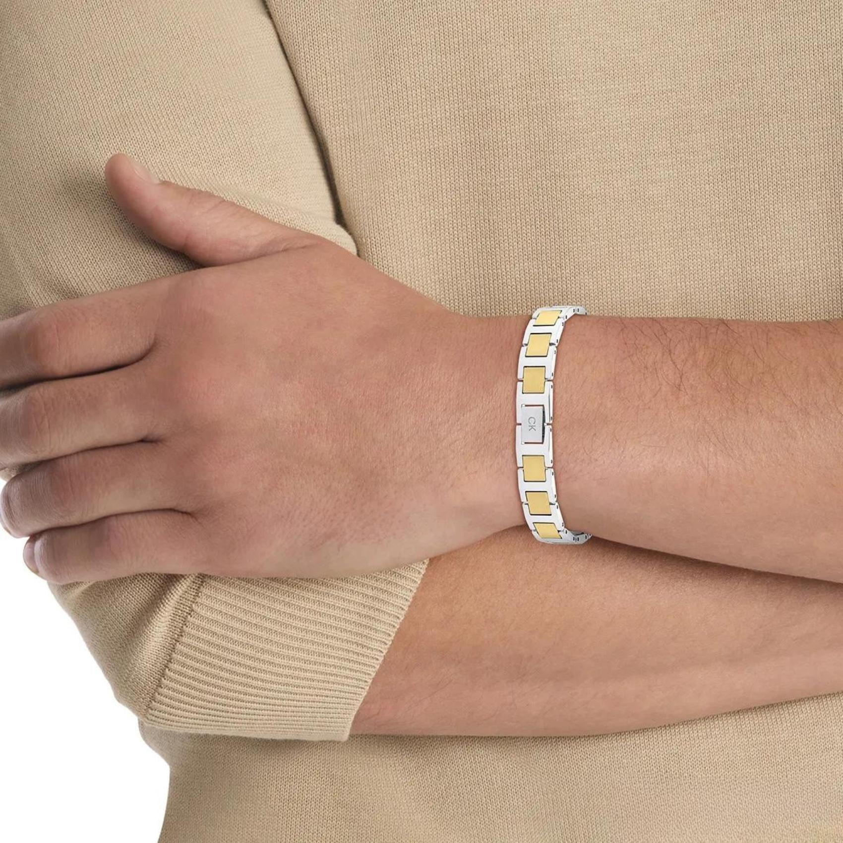 Ανδρικό βραχιόλι ταυτότητα Calvin Klein 35100009 δίχρωμο σε ασημί-χρυσό χρώμα κατασκευασμένο από χειρουργικό ατσάλι σε σχέδιο μπρασελέ, φορεμένο.