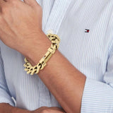 Ανδρικό ατσάλινο βραχιόλι Tommy Hilfiger 2790638 χειροπέδα σε χρυσό χρώμα και σχέδιο αλυσίδας με διαγώνια πλέξη, φορεμένο.