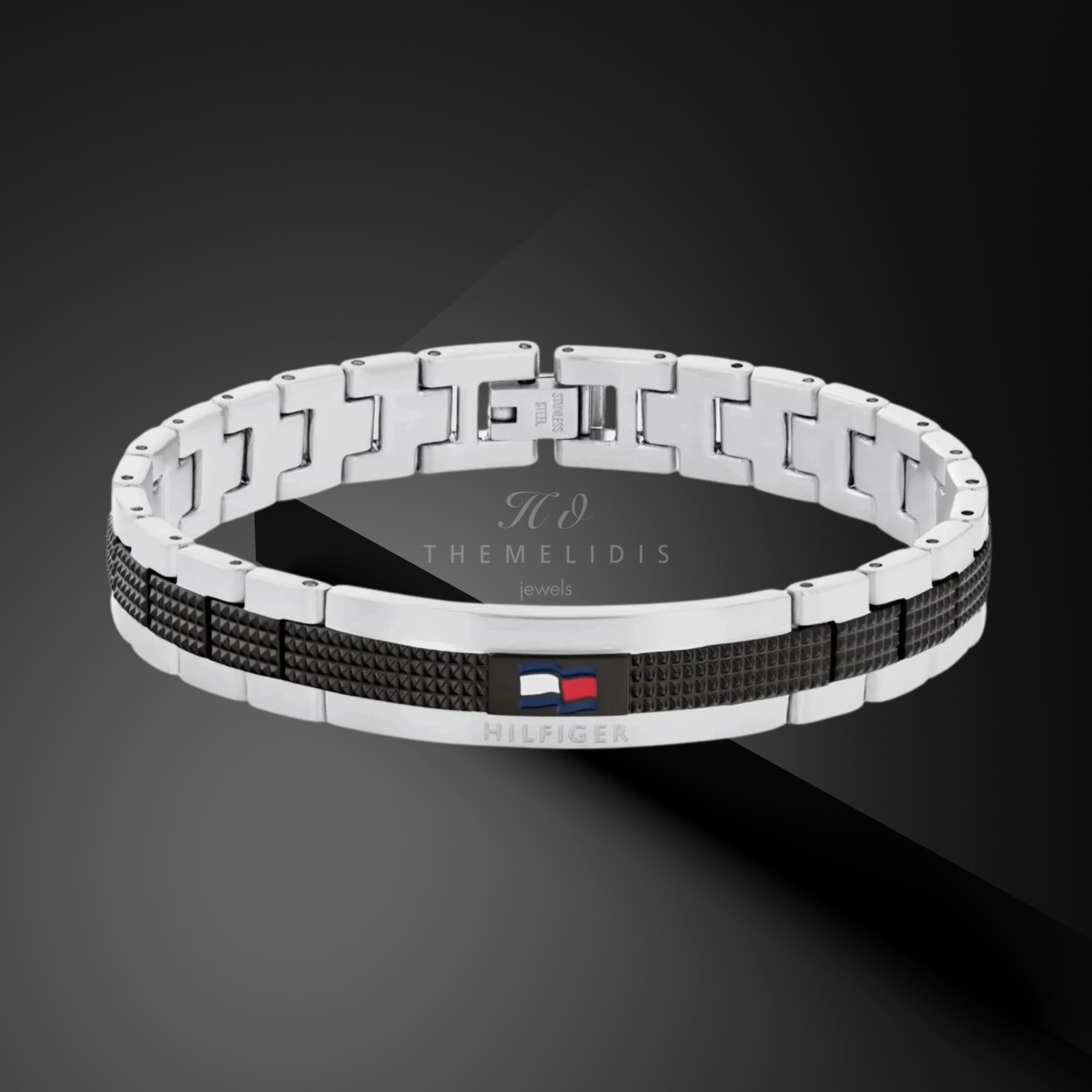 Ανδρικό ατσάλινο βραχιόλι Tommy Hilfiger 2790643 χειροπέδα σε ασημένιο χρώμα με μαύρες λεπτομέρεις και σχέδιο μπρασελέ, σε μαύρο φόντο.