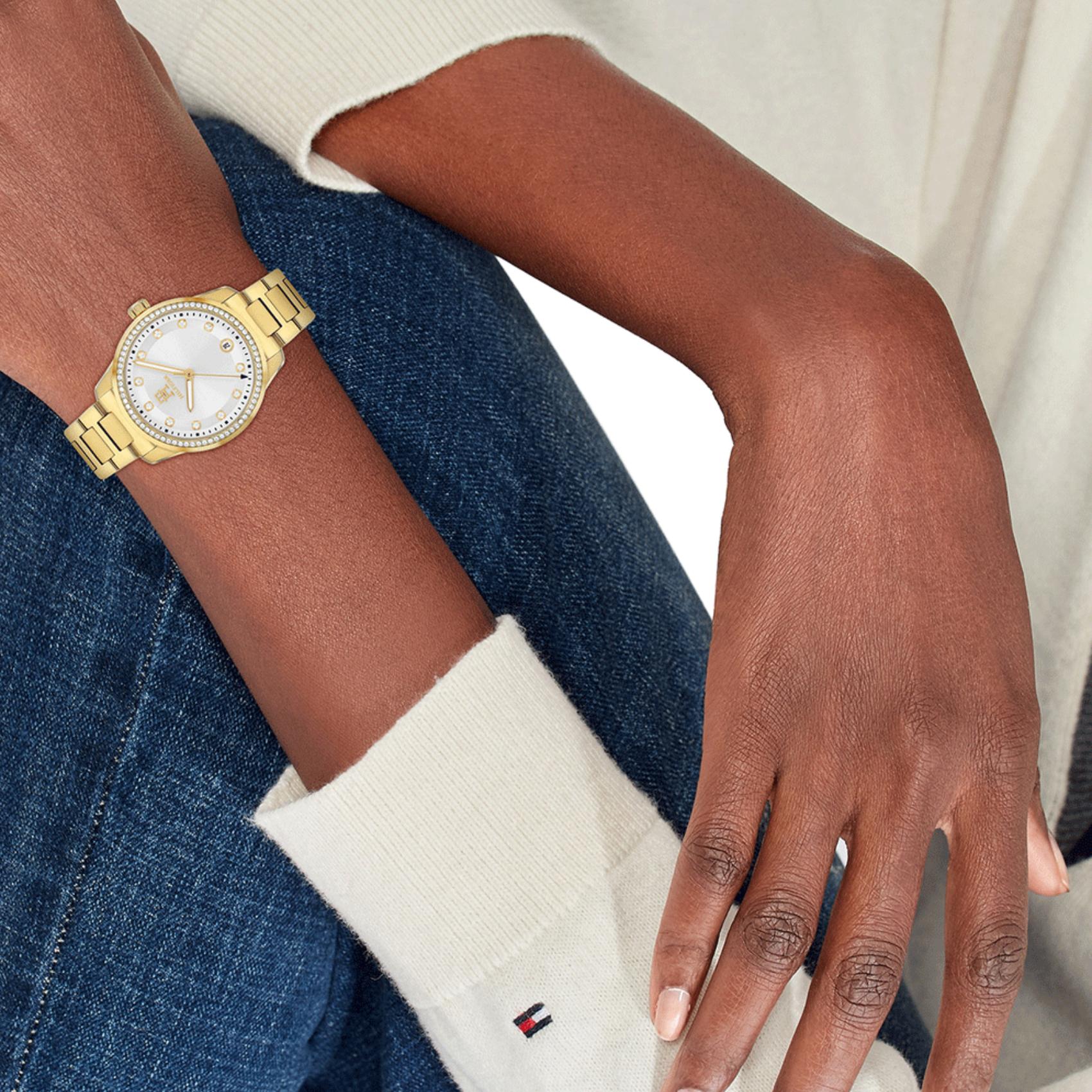 Γυναικείο ρολόι Tommy Hilfiger TH85 1782758 με χρυσό ατσάλινο μπρασελέ και άσπρο καντράν διαμέτρου 36mm με ζιργκόν, φορεμένο.