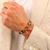 Ανδρικό δερμάτινο βραχιόλι Boss 1580700M σε καφέ χρώμα με πλεκτό σχέδιο και χρυσό κούμπωμα, φορεμένο.