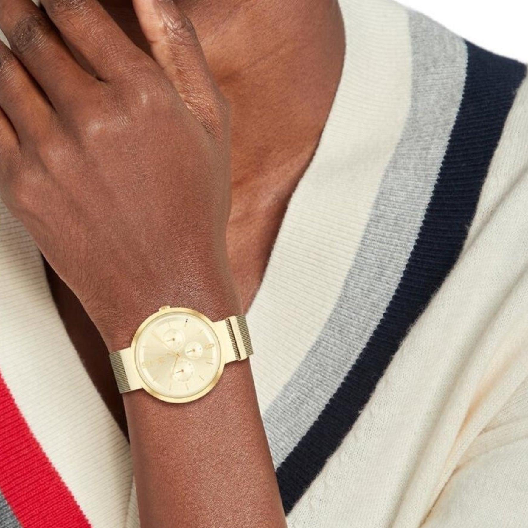 Γυναικείο ρολόι Tommy Hilfiger Lidia 1782539, με μπρασελέ σε χρυσό χρώμα από ανοξείδωτο ατσάλι και χρυσό καντράν με χρονογράφους και δείκτες σε χρυσό χρώμα φορεμένο σε γυναικείο χέρι.