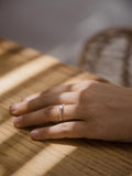 Μονόπετρο δαχτυλίδι με διαμάντι, κατασκευασμένο από λευκόχρυσο. πλαϊνές πέτρες από μικρότερα διαμάντια και καστόνι με τέσσερα δόντια, φορεμένο σε γυναικείο χέρι.
