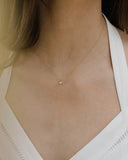 Γυναικείο χρυσό κολιέ με μονοπετράκι στο κέντρο στολισμένο με μικρά ζιργκόν περιμετρικά, φορεμένο σε μοντέλο.