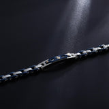 Ανδρικό βραχιόλι Maserati JM424AXU03 από ανοξείδωτο ατσάλι και κεραμικό, με ασημί-μπλε μπρασελέ και χρυσή τρίαινα σε μαύρο φόντο.