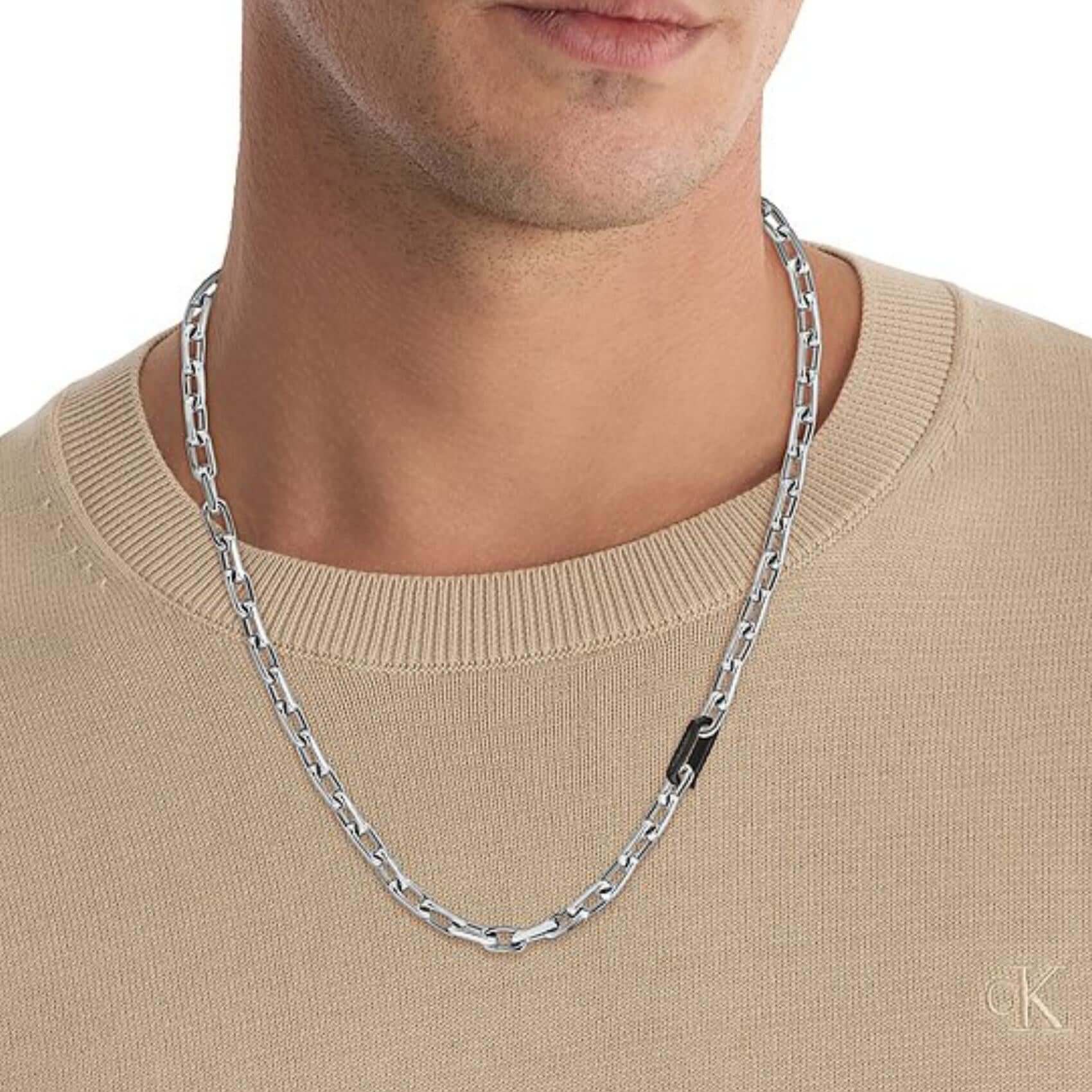 Μοντέλο φορά το ανδρικό κολιέ Calvin Klein 35100067 από ανοξείδωτο ατσάλι σε ασημί χρώμα με μαύρο κούμπωμα