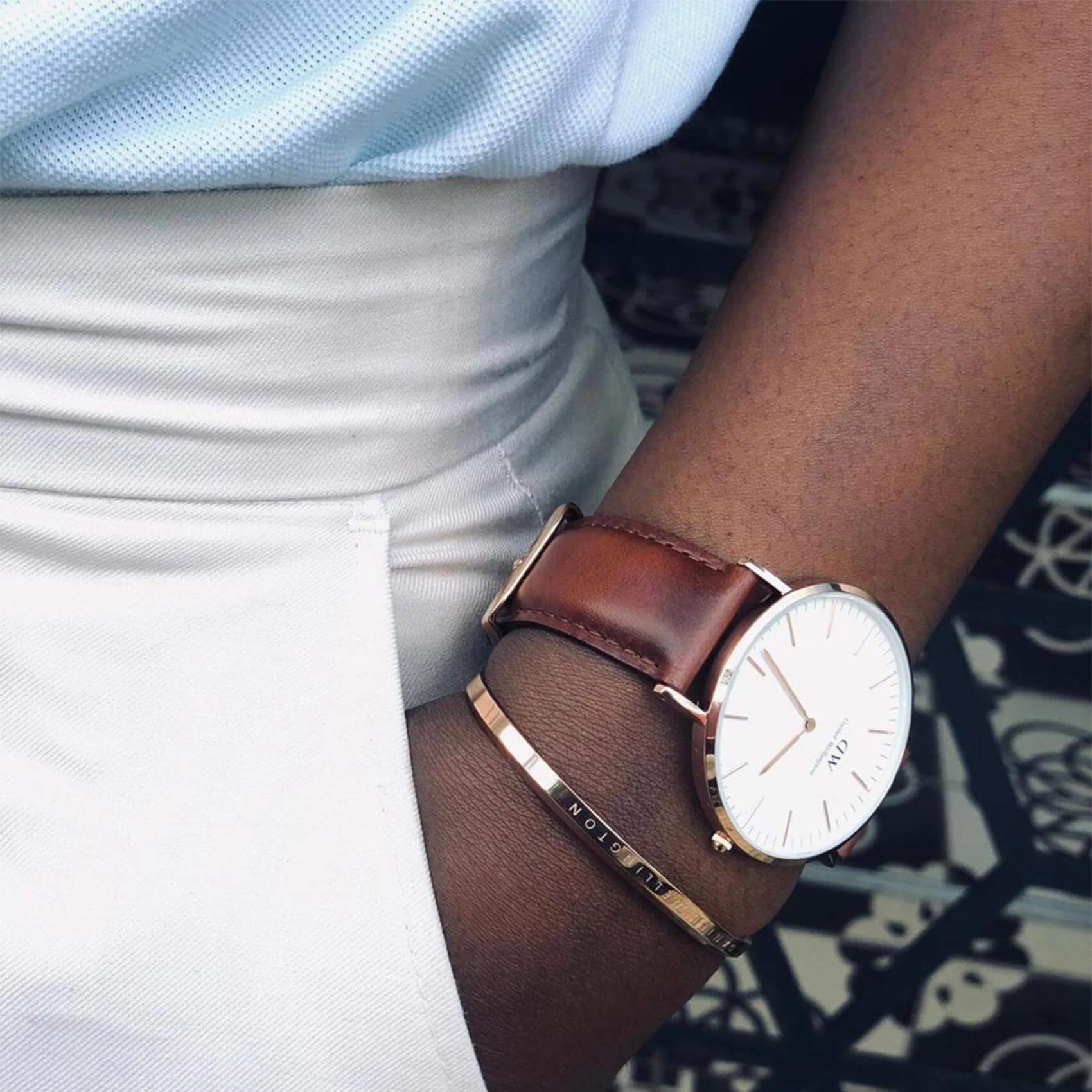 Ανδρικό ρολόι Daniel Wellington Classic St Mawes DW00100006 φορεμένο με καφέ δερμάτινο λουράκι, λευκό στρογγυλό καντράν και λεπτομέρειες σε ροζ χρυσό χρώμα.