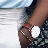 Ανδρικό ρολόι Daniel Wellington Classic St Mawes DW00100006 φορεμένο με καφέ δερμάτινο λουράκι, λευκό στρογγυλό καντράν και λεπτομέρειες σε ροζ χρυσό χρώμα.