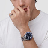 Ανδρικό ρολόι Daniel Wellington Iconic GMT DW00100921 φορεμένο με ασημί ατσάλινο μπρασελέ, μαύρο καντράν, γκρι λεπτομέρειες και μαύρη-μπλε κεραμική στεφάνη.