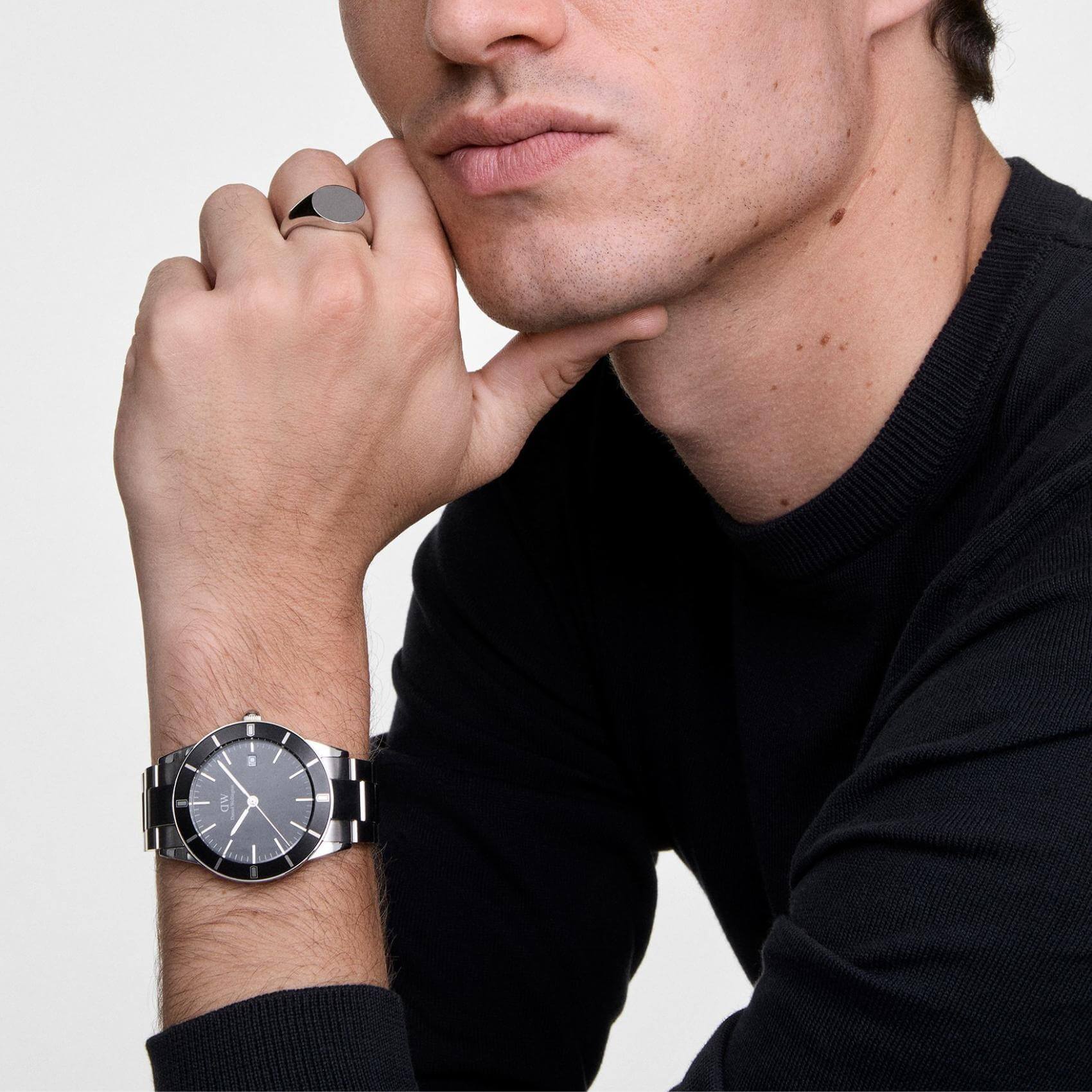 Ανδρικό ρολόι Daniel Wellington Iconic Paradigma DW00100822 φορεμένο με ασημί ατσάλινο μπρασελέ, μαύρο καντράν και γκρι λεπτομέρειες.