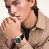 Ανδρικό ρολόι Daniel Wellington Iconic Sheffield DW00100756 φορεμένο με μαύρο δερμάτινο λουράκι, πράσινο στρογγυλό καντράν και ασημί λεπτομέρειες.