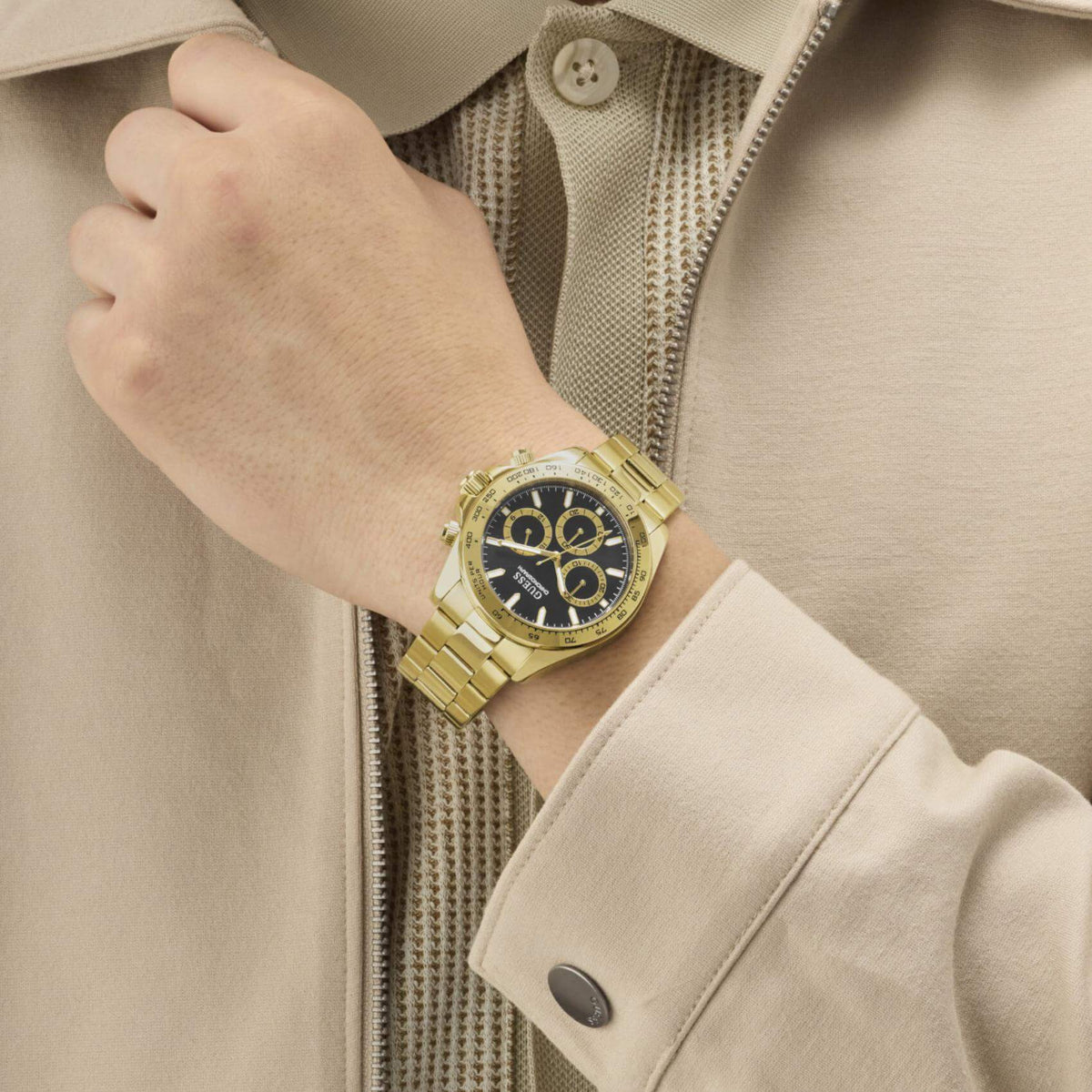 Ανδρικό ρολόι Guess Arthur GW1058G2 φορεμένο με χρυσό μπρασελέ από ανακυκλωμένο ανοξείδωτο ατσάλι, μαύρο καντράν και χρυσές λεπτομέρειες.