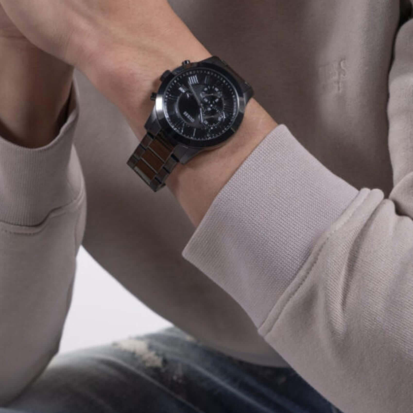 Ανδρικό ρολόι Guess Atlas W0668G5 φορεμένο με μαύρο ατσάλινο μπρασελέ, μαύρο καντράν και ασημί λεπτομέρειες.