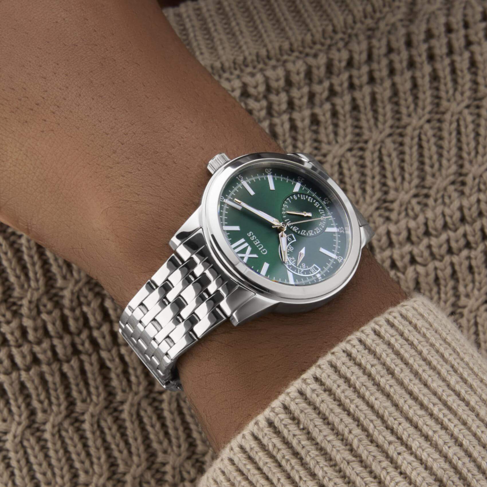 Ανδρικό ρολόι Guess Emerson GW0976G5 φορεμένο με ασημί ατσάλινο μπρασελέ, πράσινο καντράν και ασημί λεπτομέρειες.