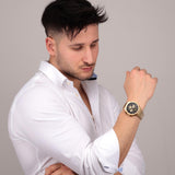 Φωτογραφία του ανδρικού ρολογιού Maserati Stile R8873642001 χρονογράφου φορεμένο σε μοντέλο, αναδεικνύοντας το χρυσό μπρασελέ από ανοξείδωτο ατσάλι και το μαύρο καντράν με χρυσούς δείκτες.