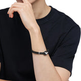 Ανδρικό βραχιόλι Emporio Armani Eagle Logo EGS3237040 φορεμένο στον καρπό, από μαύρο δέρμα με ατσάλινο στοιχείο σε ασημί χρώμα.