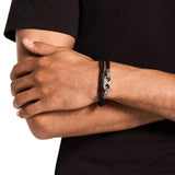 Ανδρικό βραχιόλι Emporio Armani Eagle Logo EGS3299040 φορεμένο στον καρπό, από μαύρο δέρμα με ατσάλινο στοιχείο σε ασημί χρώμα.