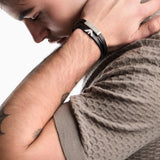 Ανδρικό βραχιόλι Emporio Armani Eagle Logo EGS3311040 φορεμένο στον καρπό, από μαύρο δέρμα με ατσάλινο στοιχείο ταυτότητας σε ασημί χρώμα.