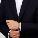 Ανδρικό βραχιόλι Maserati Iconic JM425AVD108 φορεμένο σε ανδρικό χέρι, σε ασημί με χρυσή τρίαινα.