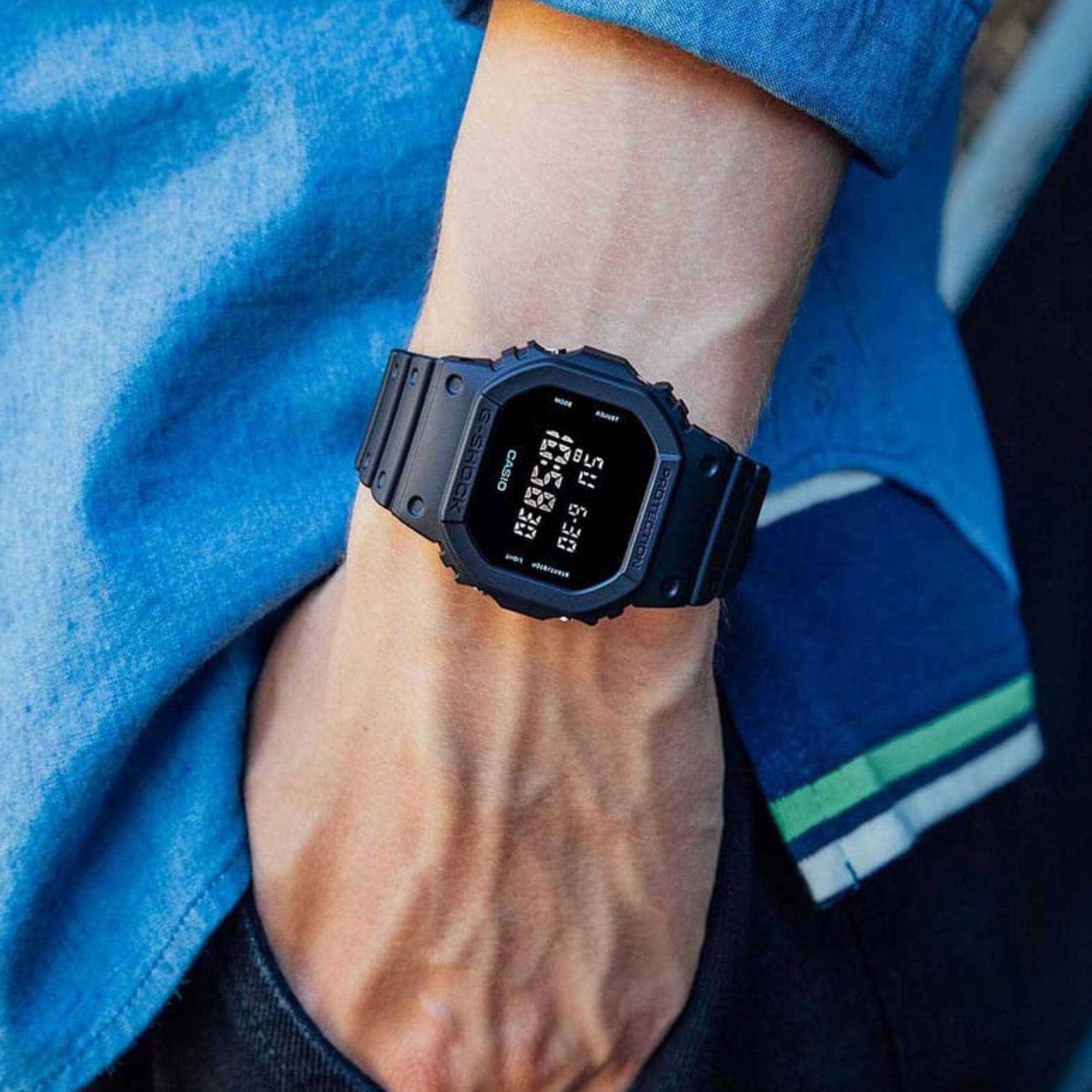 Ανδρικό ρολόι Casio G-Shock DW-5600UBB-1ER φορεμένο στον καρπό με μαύρο καουτσούκ λουράκι και μαύρο ψηφιακό καντράν.