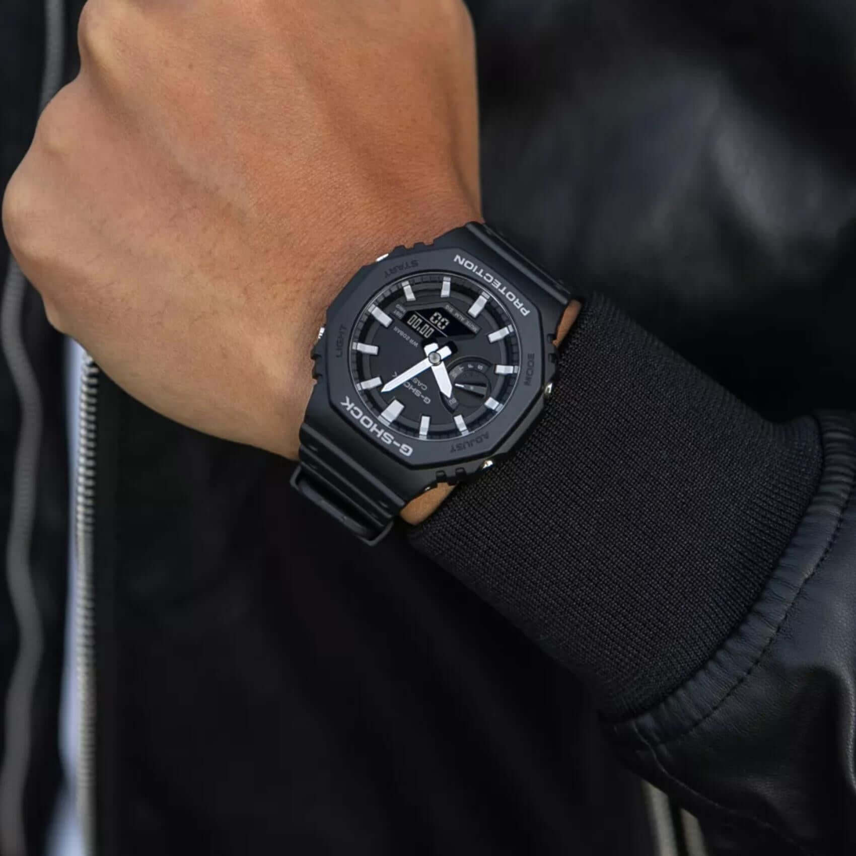Ανδρικό ρολόι Casio G-Shock GA-2100-1AER φορεμένο στον καρπό με μαύρο καουτσούκ λουράκι και μαύρο καντράν.