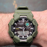 Ανδρικό ρολόι Casio G-Shock GA-B010-3AER φορεμένο στον καρπό με χακί καουτσούκ λουράκι και μαύρο καντράν.