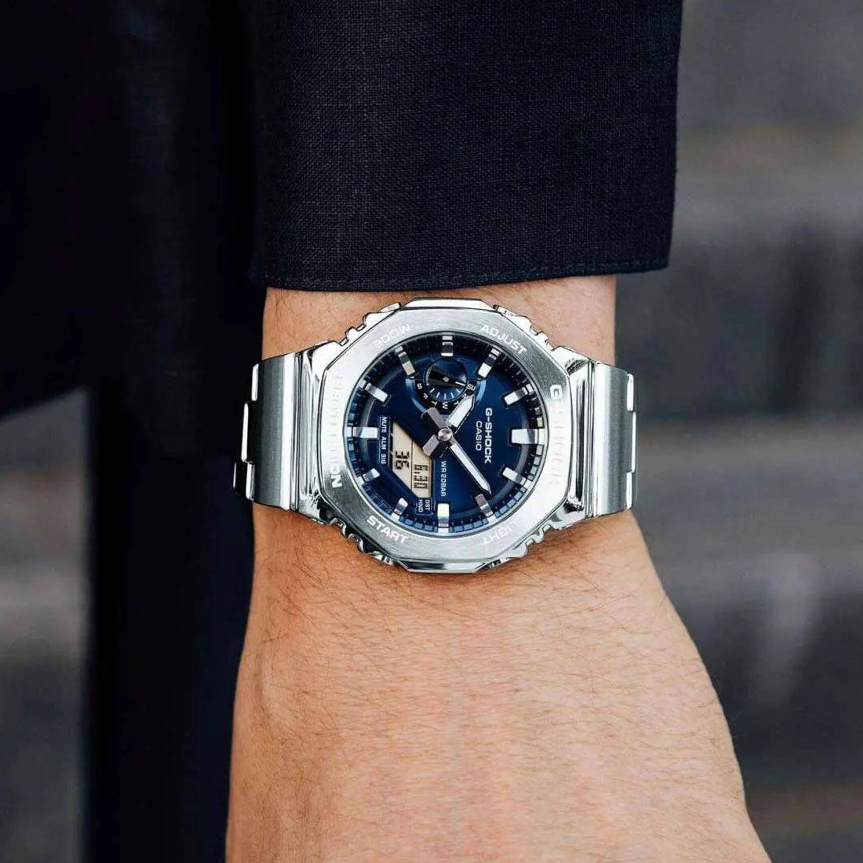 Ανδρικό ρολόι Casio G-SHOCK GM-2110D-2BER φορεμένο στον καρπό με ασημί ατσάλινο μπρασελέ και μπλε καντράν.