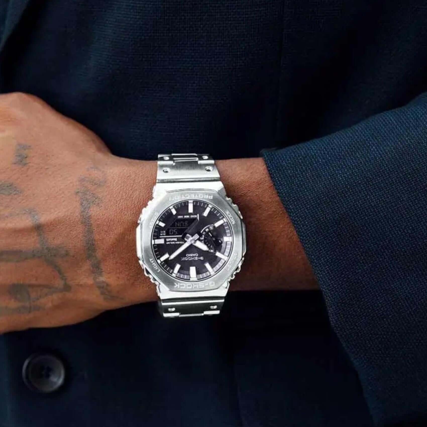 Ανδρικό ρολόι Casio G-SHOCK GM-B2100SD-1AER φορεμένο στον καρπό με ασημί ατσάλινο μπρασελέ και μαύρο καντράν.
