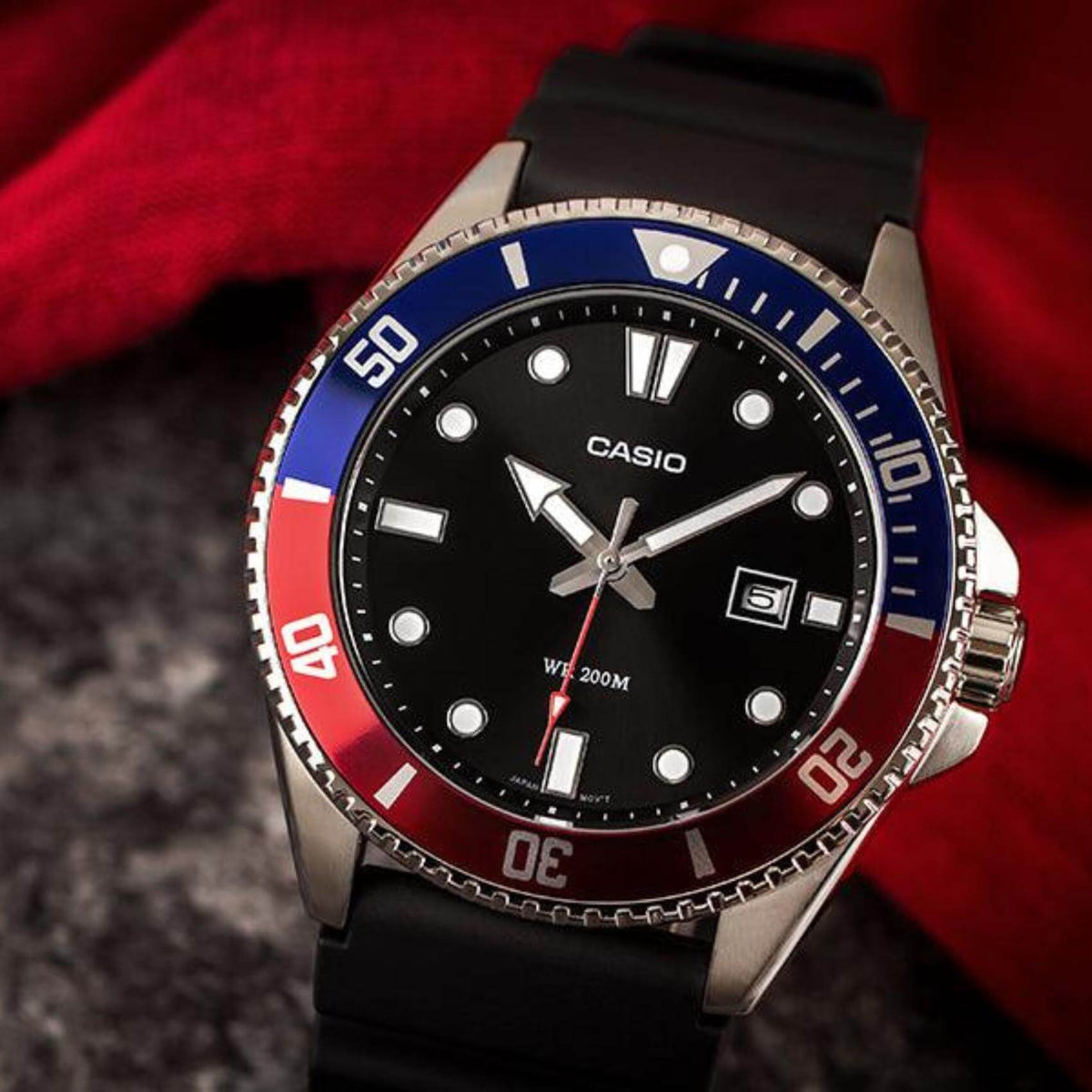 Καταδυτικό ρολόι CASIO MDV-107-1A3VEF με μαύρο λουράκι από καουτσούκ, μαύρο καντράν με φωσφορίζον δείκτες, περιστρεφόμενη στεφάνη σε κόκκινο μπλε χρώμα και ένδειξη ημερομηνίας.