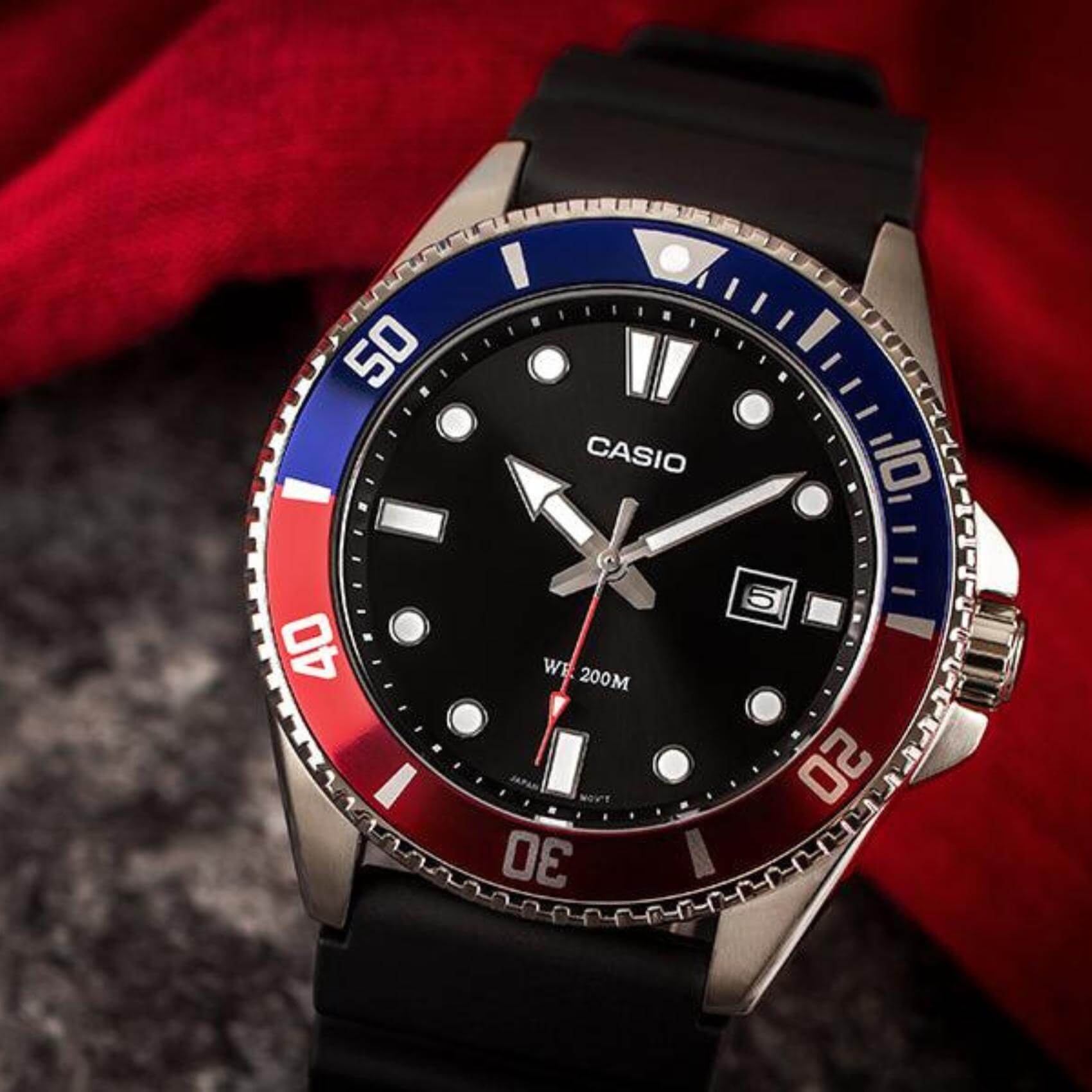 Καταδυτικό ρολόι CASIO MDV-107-1A3VEF με μαύρο λουράκι από καουτσούκ, μαύρο καντράν με φωσφορίζον δείκτες, περιστρεφόμενη στεφάνη σε κόκκινο μπλε χρώμα και ένδειξη ημερομηνίας.