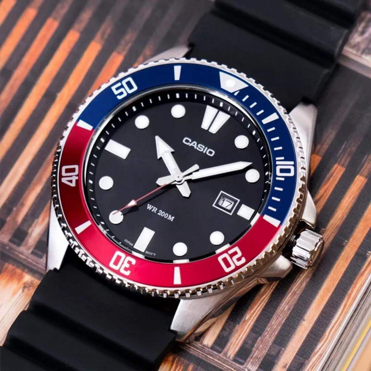 Καταδυτικό ρολόι CASIO MDV-107-1A3VEF με μαύρο λουράκι από καουτσούκ, μαύρο καντράν με φωσφορίζον δείκτες, περιστρεφόμενη στεφάνη σε κόκκινο μπλε χρώμα και ένδειξη ημερομηνίας.