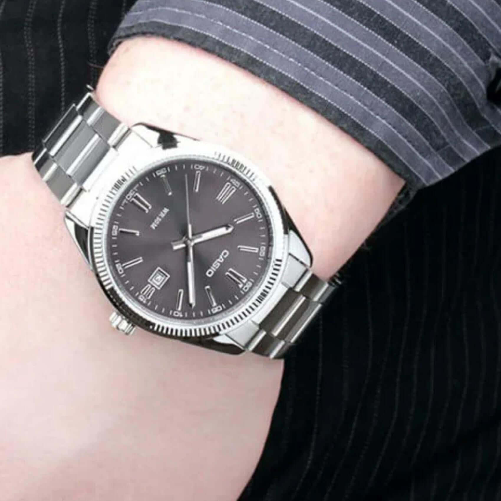 Ανδρικό ρολόι Casio Standard MTP-1302PD-1A1VEF φορεμένο στον καρπό με ασημί ατσάλινο μπρασελέ και μαύρο καντράν.