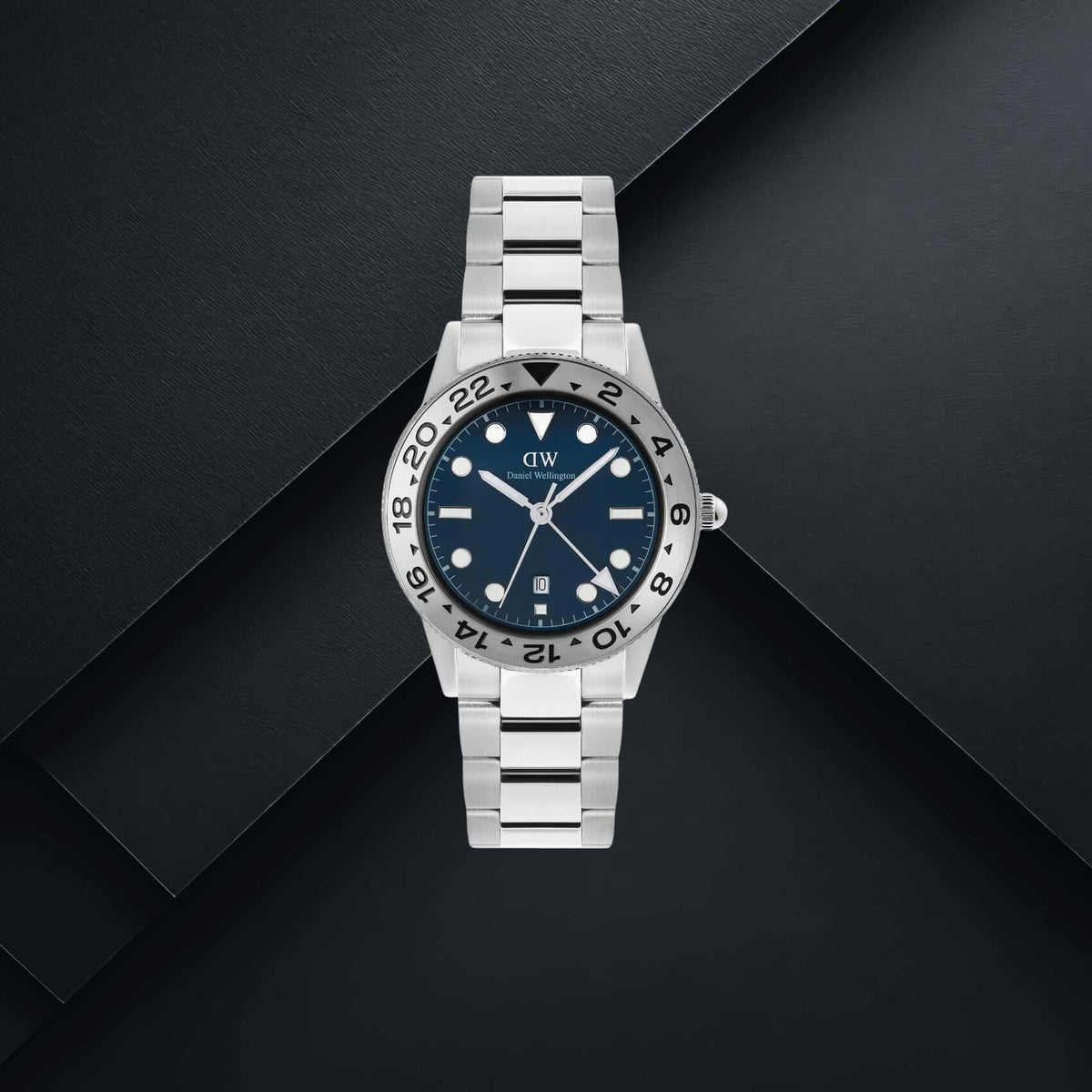 Daniel Wellington DW00100922 ανδρικό ρολόι με ασημί ατσάλινο μπρασελέ, μπλε καντράν διαμέτρου 40mm, γκρι λεπτομέρειες και γκρι κεραμική στεφάνη.