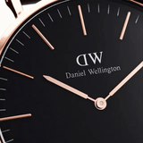 Ρολόι Daniel Wellington Petite B Melrose DW00100161 με ροζ χρυσό μπρασελέ ψάθα, μαύρο καντραν, μηχανισμό μπαταρίας και στρογγυλό στεφάνι διαμέτρου 32mm αδιάβροχο στις 3ΑΤΜ-30Μ.
