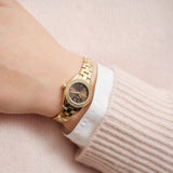 Γυναικείο ρολόι Gant Fairhaven Bijou G194103 φορεμένο στον καρπό, με χρυσό μπρασελέ και καφέ καντράν με ζιργκόν