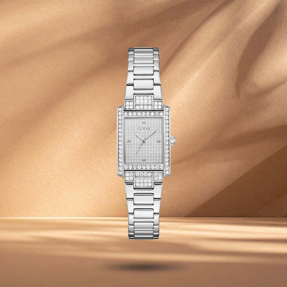Guess GW0995L1 γυναικείο ρολόι με ασημί ατσάλινο μπρασελέ, ασημί τετράγωνο καντράν μεγέθους 17x23mm και στεφάνη διακοσμημένη με ζιργκόν.