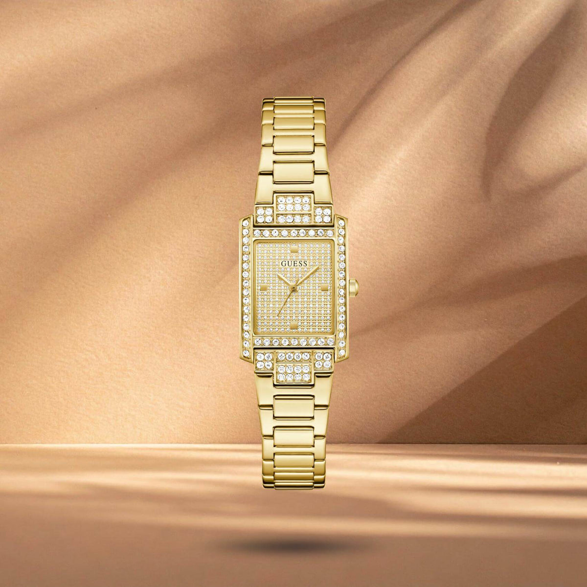 Guess GW0995L2 γυναικείο ρολόι με χρυσό ατσάλινο μπρασελέ, χρυσό τετράγωνο καντράν μεγέθους 17x23mm και στεφάνη διακοσμημένη με ζιργκόν.