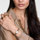 Γυναικείο ρολόι Daniel Wellington Jolie Chain Gold DW00100836 φορεμένο με χρυσό μπρασελέ αλυσίδας και λευκό τετράγωνο καντράν.