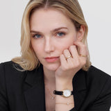 Γυναικείο ρολόι Daniel Wellington Ophelia Mini DW00100890 φορεμένο με μαύρο δερμάτινο λουράκι και λευκό οβάλ καντράν.