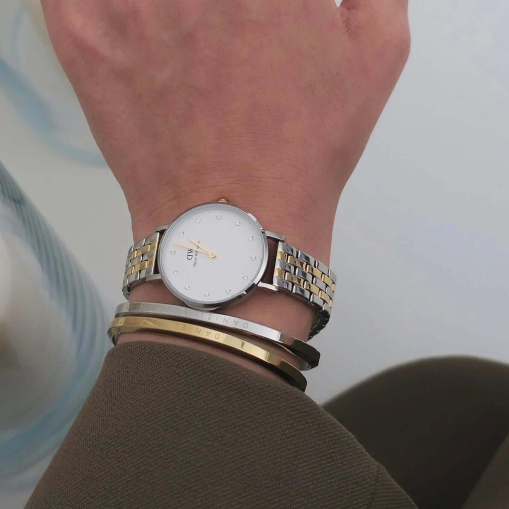 Γυναικείο ρολόι Daniel Wellington Petite Lumine DW00100616 φορεμένο με δίχρωμο ατσάλινο μπρασελέ σε ασημί-χρυσό χρώμα, λευκό στρογγυλό καντράν και χρυσούς δείκτες.