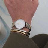 Γυναικείο ρολόι Daniel Wellington Petite Lumine DW00100616 φορεμένο με δίχρωμο ατσάλινο μπρασελέ σε ασημί-χρυσό χρώμα, λευκό στρογγυλό καντράν και χρυσούς δείκτες.