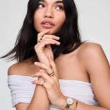 Γυναικείο ρολόι Daniel Wellington Petite Roman Numerals DW00100857 φορεμένο με χρυσό ατσάλινο μπρασελέ και λευκό καντράν με μπλε δείκτες.