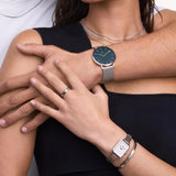Γυναικείο ρολόι Daniel Wellington Quadro Lumine DW00100625 φορεμένο με δίχρωμο ατσάλινο μπρασελέ σε ασημί και χρυσό χρώμα και λευκό τετράγωνο καντράν.