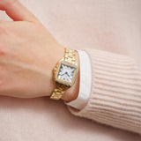 Μοντέλο φορά το γυναικείο ρολόι Gant Seneca Bijou G193103 με χρυσό μπρασελέ και λευκό τετράγωνο καντράν, αναδεικνύοντας τον κομψό και λαμπερό σχεδιασμό του