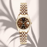 Γυναικείο ρολόι Gant Sussex Mini Bijou G181103 με χρυσό μπρασελέ και καφέ καντράν 28mm με ζιργκόν, σε μπεζ φόντο.