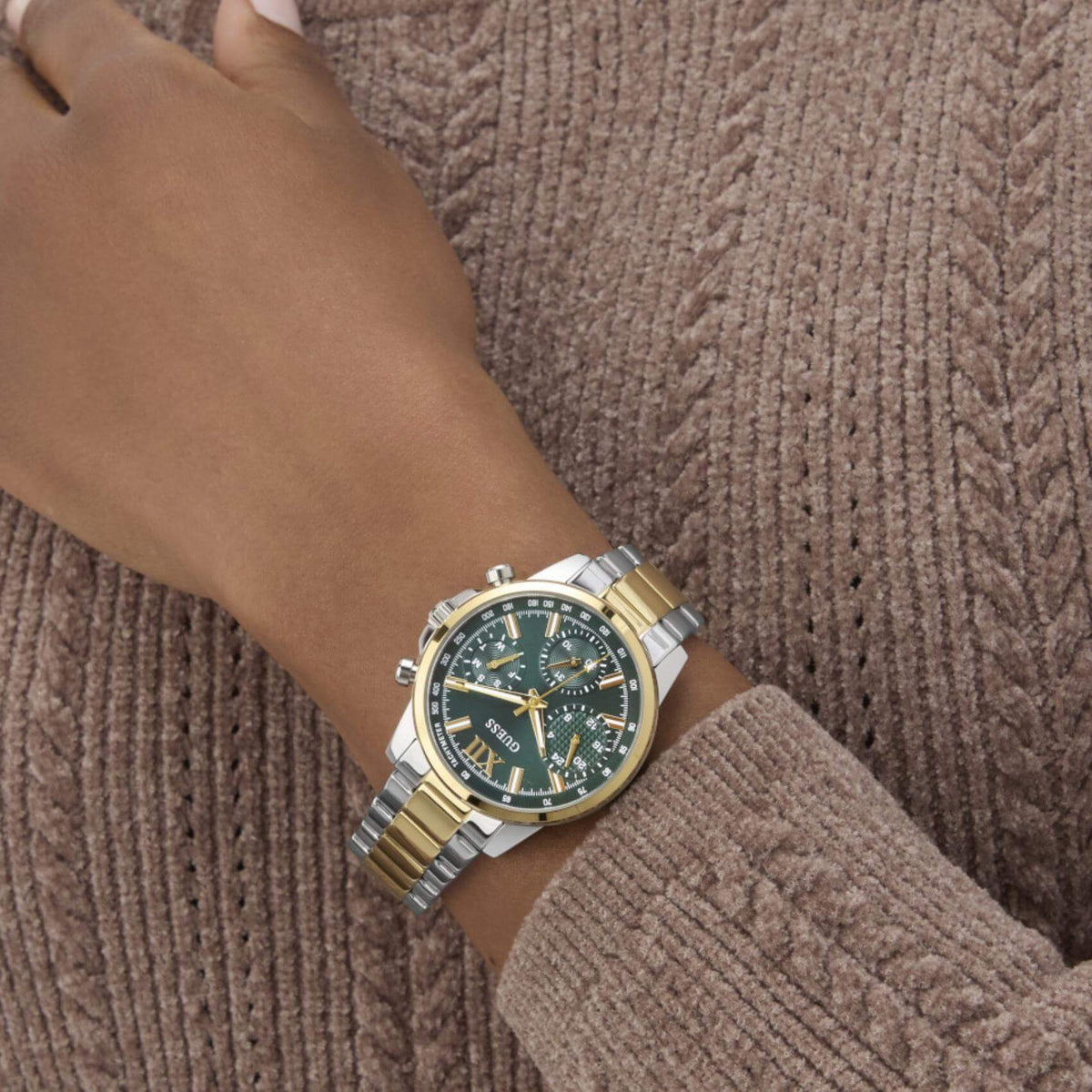 Γυναικείο ρολόι Guess Bailey GW0933L7 φορεμένο με δίχρωμο ατσάλινο μπρασελέ σε ασημί και χρυσό χρώμα, πράσινο καντράν και χρυσές λεπτομέρειες.