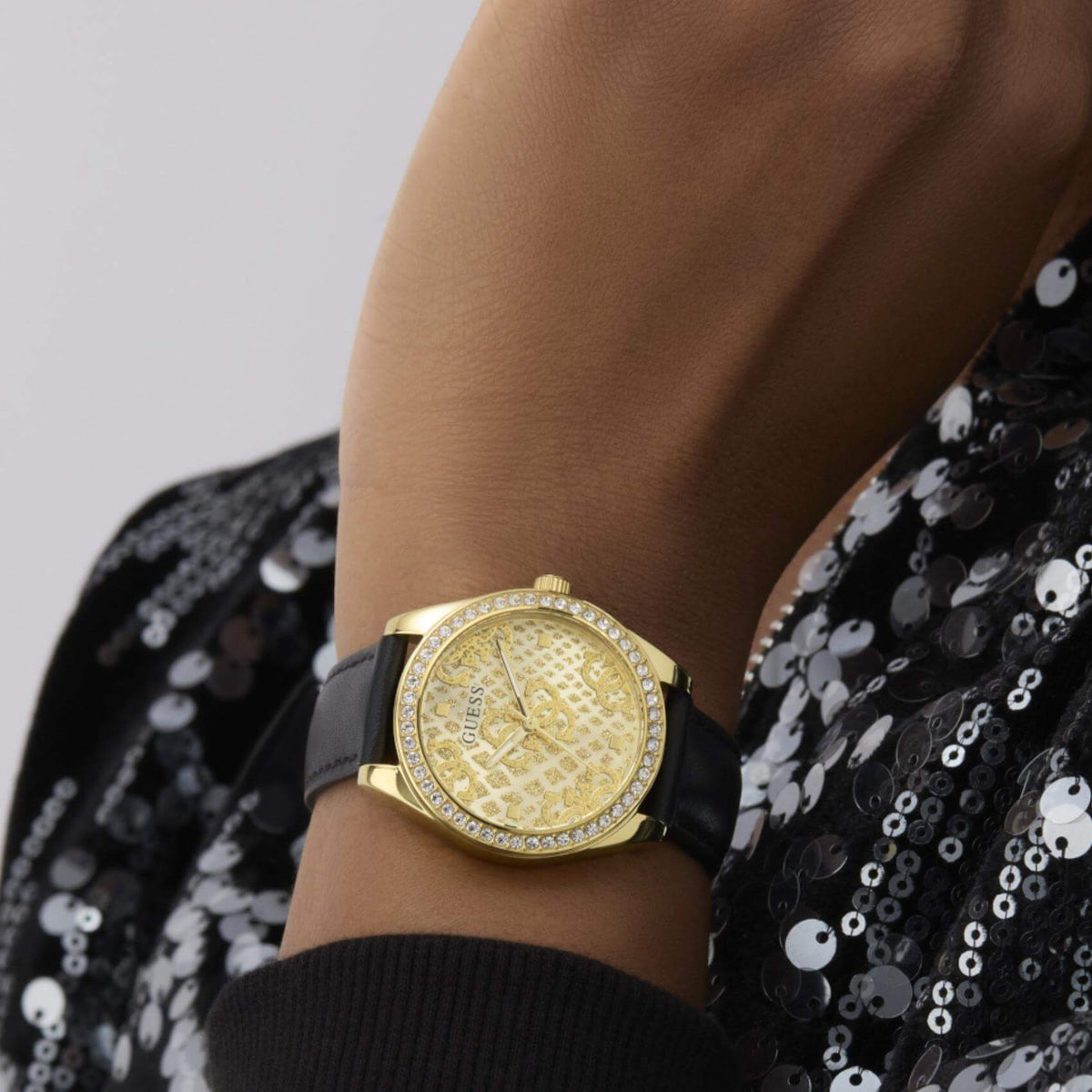 Γυναικείο ρολόι Guess Boa GW0989L2 φορεμένο με μαύρο δερμάτινο λουράκι, χρυσό καντράν και λαμπερά ζιργκόν.