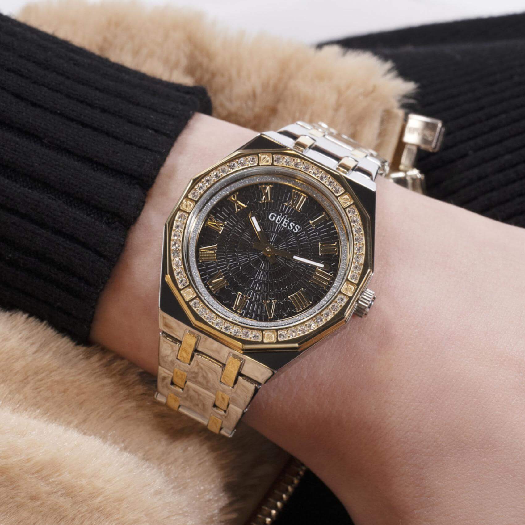 Γυναικείο ρολόι Guess Desire GW0770L4 φορεμένο με δίχρωμο ατσάλινο μπρασελέ σε ασημί και χρυσό χρώμα, μαύρο καντράν, χρυσές λεπτομέρειες και στεφάνη με ζιργκόν.