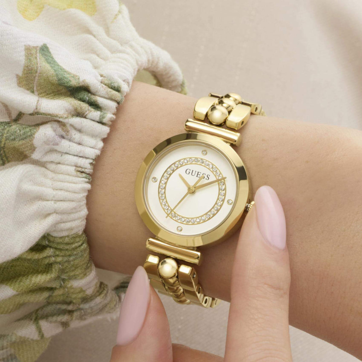Γυναικείο ρολόι Guess Leena GW0994L2 φορεμένο με χρυσό μπρασελέ και λευκό καντράν.