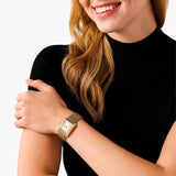 Γυναικείο ρολόι Michael Kors Emery MK4826 φορεμένο στον καρπό, με χρυσό ατσάλινο μπρασελέ και λευκό τετράγωνο καντράν 27mm με ζιργκόν